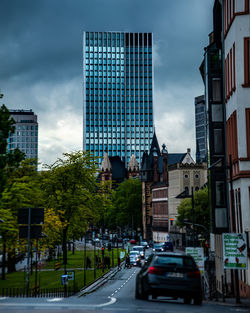 Road by buildings in city against sky