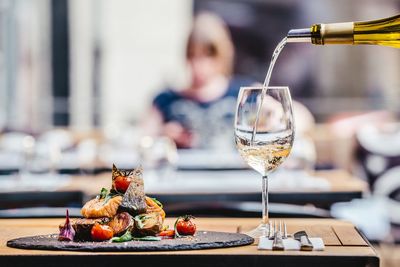 Wine pouring in wineglass by food on table at restaurant