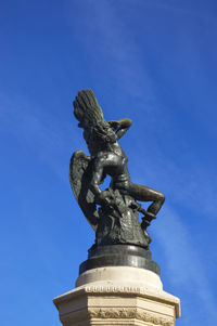 Low angle view of statue against blue sky