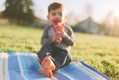 Close-up of boy sitting ice cream cone while sitting in park