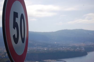 Close-up of sign on mountain against sky