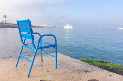 Deck chairs on beach against sky