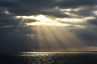 Sunlight streaming through clouds over sea