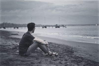 Side view of man sitting on beach