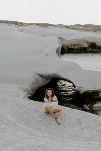 Young woman sitting on rock at beach