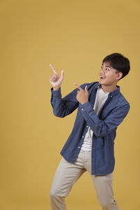 Young man looking away against orange background