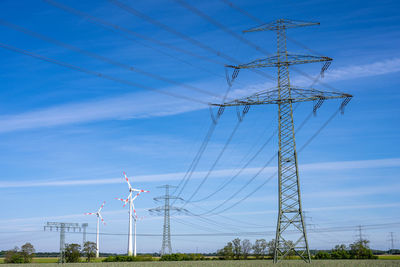 Electricity pylon and power lines with wind turbines in the background