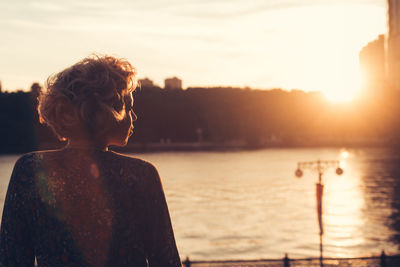 Rear view of woman looking at river during sunset