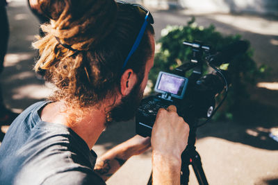 Young man with video camera by tree trunk