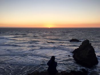 Silhouette woman standing on beach against clear sky during sunset