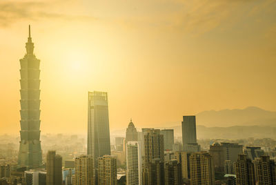 Modern buildings in city against sky during sunset