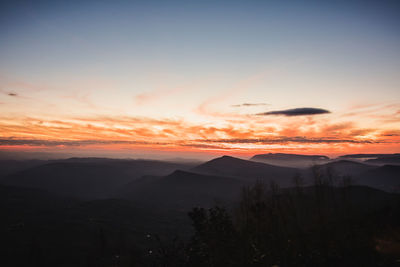 Scenic view of silhouette mountains against orange sky