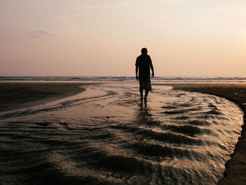 Silhouette of woman standing on beach at sunset