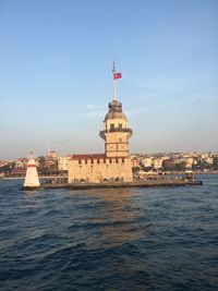 Lighthouse on sea against buildings in city