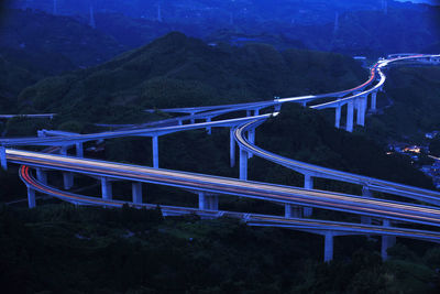 Light trails on bridge against mountain at night