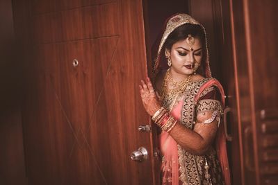 Young bride in traditional clothing standing by door