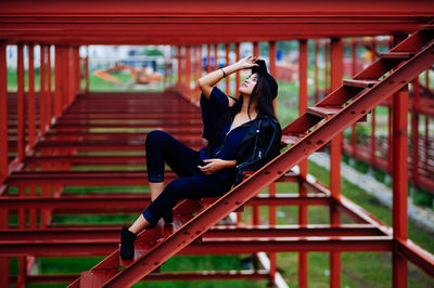 Young woman looking away while lying on ladder