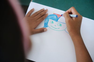 High angle view of girl drawing on paper