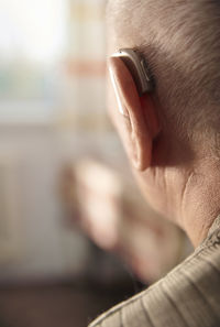 Senior man wearing hearing aid at home