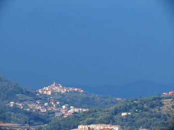 Aerial view of townscape and mountains against clear blue sky