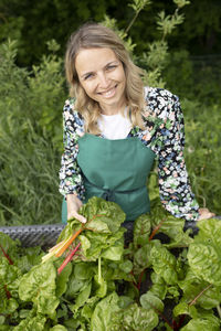 Portrait of smiling young woman standing against plants