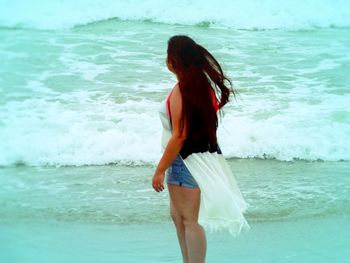 Beautiful woman standing at beach against sky