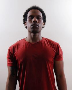 Portrait of man in red t-shirt standing against white background