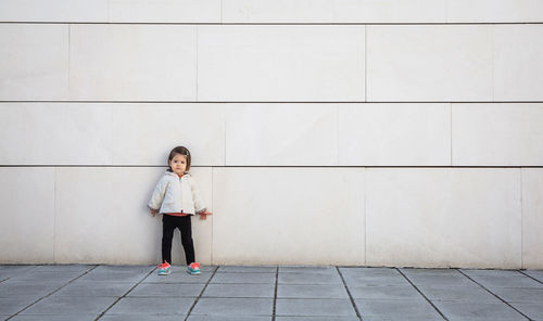 Full length of girl standing against wall