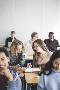 Female students discussing over book in classroom