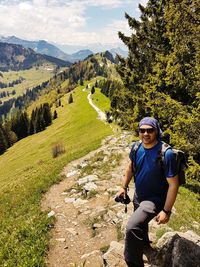 Portrait of smiling man sitting in forest against sky