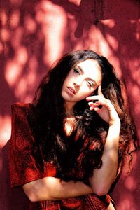 Portrait of young woman standing against wall