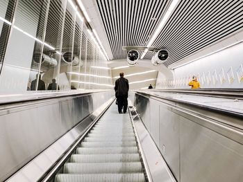Rear view of man standing on escalator