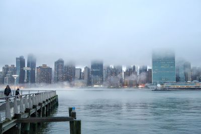 River by buildings in city against sky