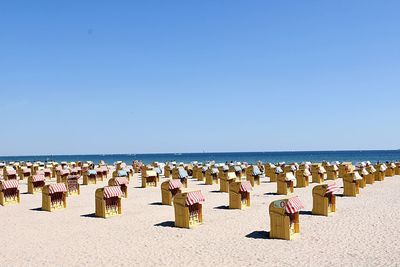 Scenic view of hooded beach chairs on sand against clear sky