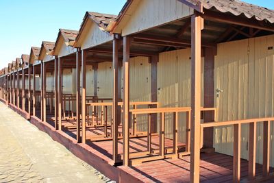 Wooden house by building against sky