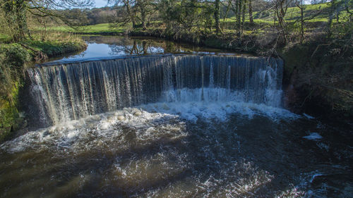 Scenic view of waterfall against sky