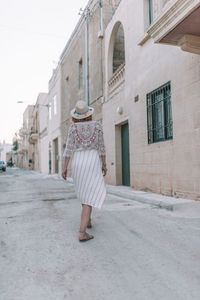 Rear view of woman walking on street amidst buildings
