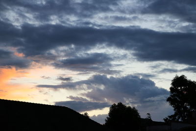 Low angle view of silhouette trees against dramatic sky