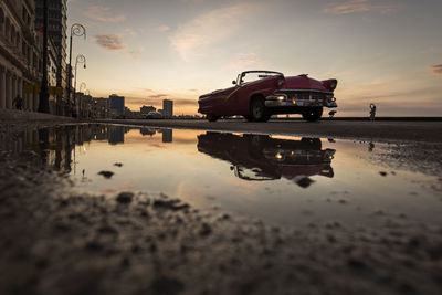 Reflection of building in puddle at sunset