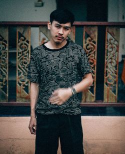 Portrait of young man standing against railing