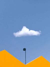 Low angle view of yellow flag against blue sky