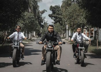 Portrait of people riding motorcycle on road