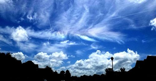 Low angle view of silhouette buildings against blue sky