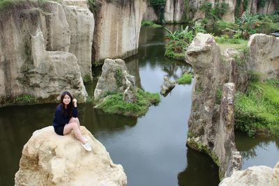 High angle view of woman sitting on cliff by sea