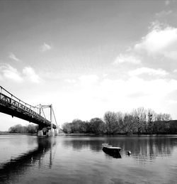 Bridge over river against cloudy sky