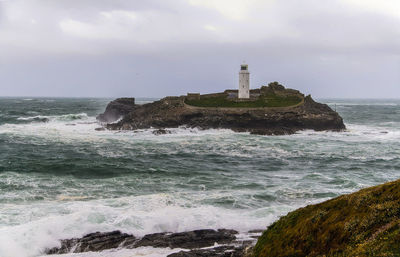 Lighthouse by sea against sky