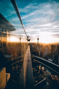 Reflection of buildings on railing in city against sky