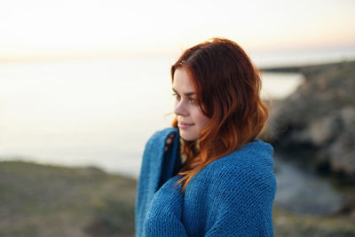 Young woman looking at beach against sky