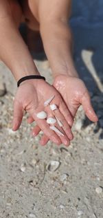 Close-up of hands holding sand at beach