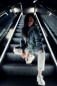 Full length portrait of young woman on escalator